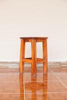 A wooden stool sitting on a tiled floor photo