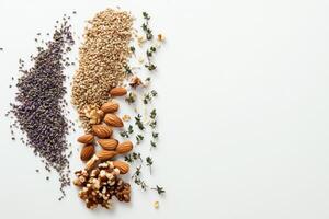 Discover a variety of organic ingredients including seeds, nuts, and herbs arranged on a white background, allowing ample space for text. photo