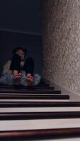 Naughty boy trying to slide by the stairs on the pillow. Teenager sits on the soft fluffy pillow descending step by step indoors. Vertical video