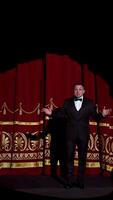 Announcer on a stage in theater. Bright round light on one person. man in black suit performs to the auditorium. Vertical video