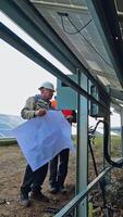 Workers installing photovoltaic panels. Technicians install the electrical system of sunny battery. View under the solar battery. Vertical video