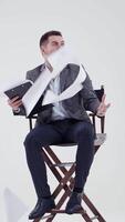 Businessman in a chair shouting. Many papers are flying in the studio and a man in suit with opened mouth. Slow motion. Vertical video
