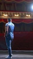 Actor on classic theatre stage. Man is speaking in spotlights during the performance. Back view . Vertical video