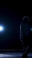 Senior man in costume on stage in darkness. Active man in hat dancing on stage during the performance in the theater. Vertical video