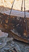 Crane lifting heavy rock. Heavy natural granite stone blocks stacked for processing Vertical video