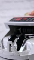 Electronic counting machine. Counter machine with US money banknotes of 100 dollars. Bank automatic equipment for counting cash money. Vertical video
