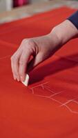 Seamstress working with pattern. View of seamstress measuring the material with a tape Vertical video