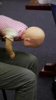 Practical course on a doll dummy. Female practitioner teaching to reanimate patient on a baby mannequine. Instructor demonstrate the training exercise. Vertical video