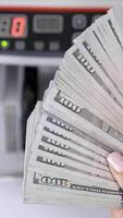 hundert Dollar Rechnungen im weiblich Hände. viel amerikanisch Papier Geld im Hände auf das Hintergrund von elektronisch rechnen Maschine. Nahansicht. Vertikale video