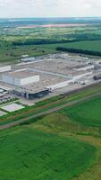 Large industrial zone on green field. Factory surrounded by beautiful landscape in summer. Aerial view. Camera moving back. video