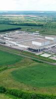 Modern factory in rural place. Innovative complex of industrial plant on green nature background. Industrial zone on fields. Aerial view. Vertical video