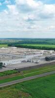 Beautiful white factory among nature.Large industrial area of a modern plant with car parking surrounded by green fields and forests. Vertical video