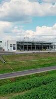Industrial zone in the countryside. Factory construction near the highway on green nature background. Modern manufacturing under the sky. Vertical video