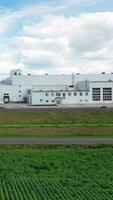 Truck is moving on a road on the background of factory. Modern industrial plant with white buildings near the highway. Vertical video