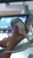 Obstetrician holds the sensor and presses keys on the ultrasound machine. Doctor starts the check up of a pregnant lady. Vertical video