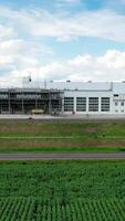Large innovative plant under the sky. Modern industry with white buildings on field. Front view. Motion camera to the right. Vertical video