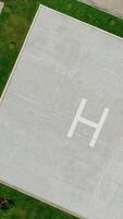 Empty parking space. Square place for parking cars with the letter H in the center. Modern parking on field. Top aerial view. Motion down. Vertical video