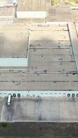 Roofs of the industrial plant. Many buildings constructed together and car parking places of a large modern factory. Top view. Vertical video