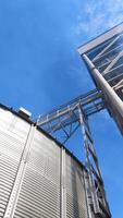 Drying grain on a modern factory. Large grain elevator and smoke from industry. Vapor releases from industrial plant during grain processing. Vertical video