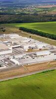 Aerial view of modern storage warehouse with many trucks on parking lot. Industrial zone on city suburb. Vertical video