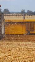 Agriculture machine harvesting crop in fields. Special technic in action. Agricultural technic in field. Heavy machinery, blue sky above field. Vertical video