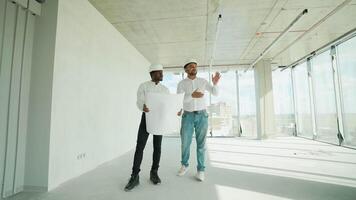 Two diverse construction workers working together while visiting a new building video
