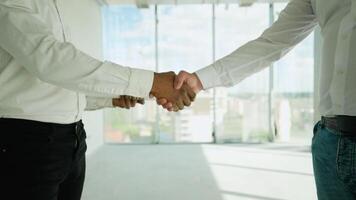 Two multiethnic builders shaking hands on construction site. Handshake of partner video