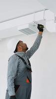 Indian worker install ducted pipe system for ventilation and air conditioning in office. Hvac technician at work. Vertical video