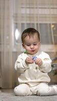 Sweet Caucasian child sits on the floor holding a pacifier in mouth. Baby crawls quickly to camera and then turns to Christmas tree. Vertical video