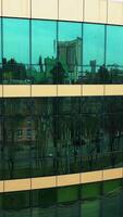Facade of modern glass building. Surface of glass building with the city reflection. Vertical video