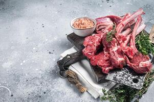 Butcher cutting board with butchered Raw Lamb chop steak or mutton cutlet. Gray background. Top view. Copy space photo