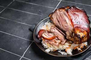 Roast Pork Ham Hock, knuckle with Sauerkraut on a plate. Black background. Top view. Copy space photo
