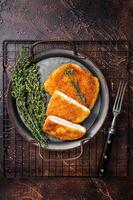 Cordon bleu chicken fillet cutlet with ham and cheese. Dark background. Top view photo