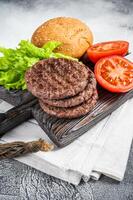 Fried cutlet for burger with vegetables and spices on wooden board. White background. Top view photo