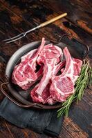 Raw lamb mutton chop steaks, fresh meat cutlets on butcher table. Black background. Top view photo