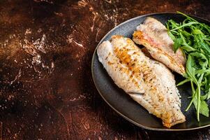 Roasted Snapper, sea red perch fillet on a plate with salad. Dark background. Top view. Copy space photo