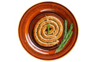 Grilled spiral sausage from pork and beef meat on a rustic plate. Isolated on white background. photo