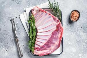 Ready for cooking Rack of lamb, raw mutton ribs with herbs. Gray background. Top view photo