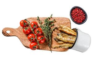 Fried smelt in the pan on the table with tomatoes and pepper. Isolated on white background. Top view photo