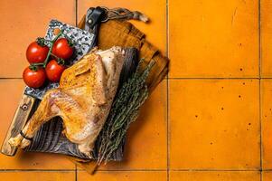 Grilled guinea fowl with herbs and spices on butcher board, cooked game bird. Orange background. Top view. Copy space photo