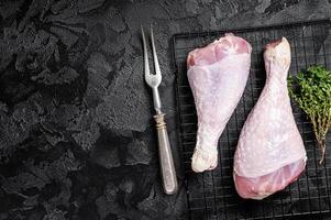 Raw turkey legs on a butcher table. Black background. Top view. Copy space photo