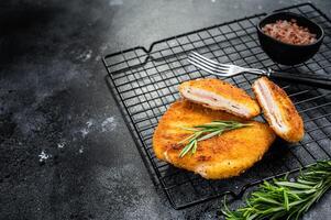 Schnitzel Cordon bleu fillet cutlet with ham and cheese. Black background. Top view. Copy space photo