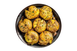 Broken potatoes baked in oil with herbs. Isolated on white background. photo
