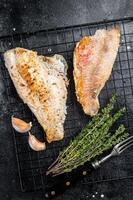 Grilled sea red perch fillet, Snapper fish on a rack. Black background. Top view photo