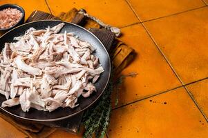 Shredded chicken meat in a plate. Orange background. Top view. Copy space photo