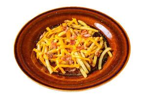 French fries with melted cheddar cheese and bacon served in a rustic plate. Isolated on white background. photo