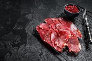 Dried sliced basturma, cured beef meat ready for eat. Black background. Top view. Copy space photo