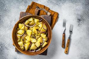 Bowl of warm potato salad with bacon, German Kartoffelsalat. White background. Top view photo
