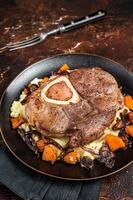 Osso buco cross cut veal shank with mashed potato on a plate. Dark background. Top view photo