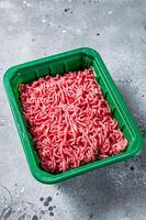 Raw Minced Meat in a Plastic Container, ground beef. Gray background. Top view photo